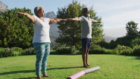 Pareja-De-Ancianos-Afroamericanos-Practicando-Yoga-Juntos-Mientras-Están-De-Pie-En-El-Jardín