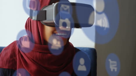 Mehrere-Digitale-Symbole-Schweben-Vor-Einer-Geschäftsfrau-Im-Hijab,-Die-Im-Büro-Ein-VR-Headset-Trägt