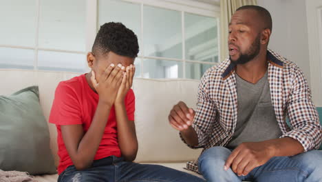 African-american-dad-talking-and-supporting-his-crying-son-at-home