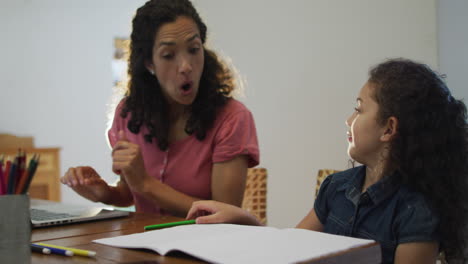 Glückliche-Gemischtrassige-Mutter-Und-Tochter,-Die-Zu-Hause-Gemeinsam-Hausaufgaben-Machen