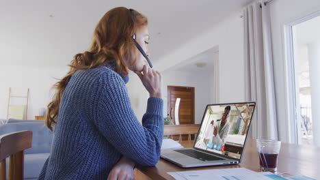 Caucasian-woman-wearing-phone-headset-having-a-video-call-with-male-colleague-on-laptop-at-home