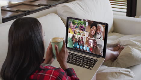 Afroamerikanische-Frau-Hält-Eine-Kaffeetasse-Und-Hält-Zu-Hause-Eine-Videokonferenz-Auf-Dem-Laptop