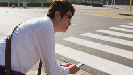 Hombre-Asiático-Sentado-En-Bicicleta-Usando-Un-Teléfono-Inteligente-En-La-Calle-De-La-Ciudad