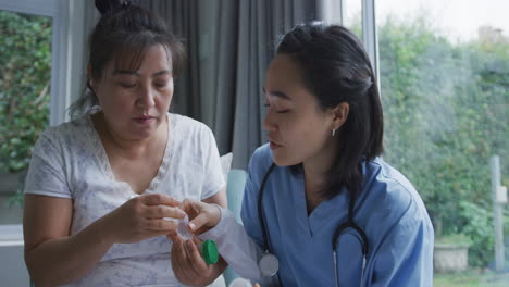 Smiling-asian-female-doctor-talking-to-happy-female-patient-about-her-medication-at-hospital