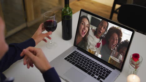 Mid-section-of-african-american-woman-drinking-wine-while-having-a-video-call-on-laptop-at-home