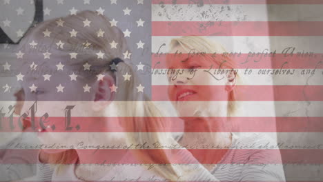 American-flag-and-constitution-text-against-caucasian-mother-brushing-hair-of-her-daughter-at-home