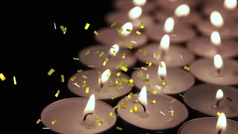 Animation-of-gold-confetti-falling-over-lit-tea-light-candles-on-black-background