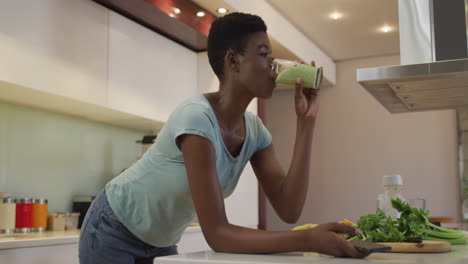 Smiling-african-american-attractive-woman-drinking-homemade-smoothie-in-kitchen