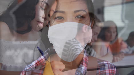 Digital-composition-of-asian-woman-wearing-face-mask-against-college-student-studying-at-college
