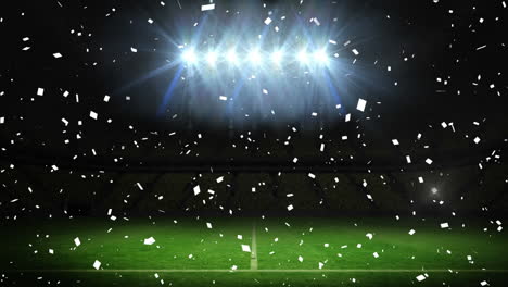 Animation-of-white-confetti-falling-over-floodlit-pitch-at-sports-stadium-at-night