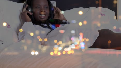 Animation-of-smiling-african-american-woman-wearing-headphones-at-home-over-cityscape