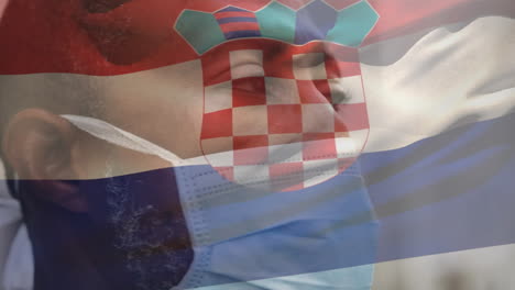 Animation-of-flag-of-croatia-waving-over-man-wearing-face-mask-during-covid-19-pandemic