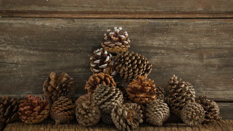 Animation-of-snow-falling-over-pine-cones-on-wood-boards