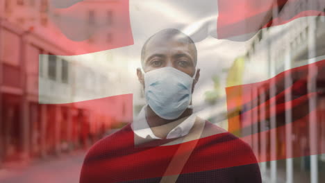 Animation-of-flag-of-switzerland-waving-over-man-wearing-face-mask-during-covid-19-pandemic