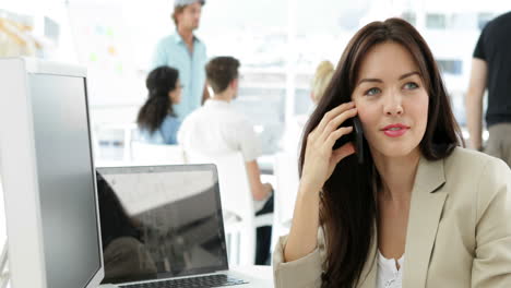 Woman-working-at-her-desk-talking-on-the-phone