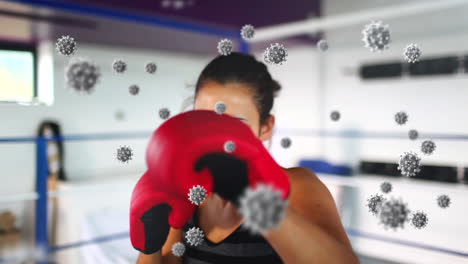 Animation-of-virus-cells-floating-over-caucasian-female-boxing