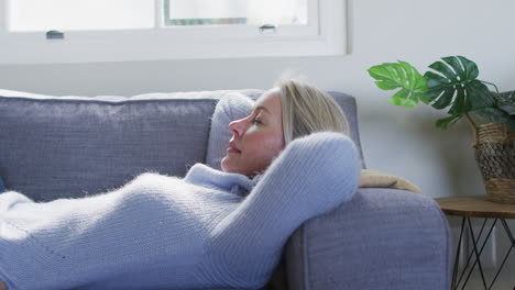 Relaxed-senior-caucasian-woman-in-living-room-lying-on-sofa