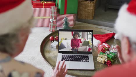 Senior-caucasian-couple-using-laptop-for-christmas-video-call-with-happy-woman-on-screen