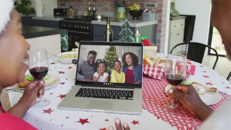 Afroamerikanisches-Paar-Mit-Wein-Und-Laptop-Für-Weihnachtsvideoanruf-Mit-Glücklicher-Familie-Auf-Dem-Bildschirm