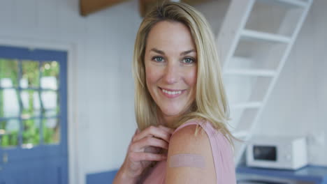 Happy-caucasian-mature-woman-showing-plaster-on-arm-where-she-was-vaccinated-against-coronavirus