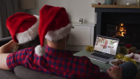 Caucasian-couple-on-video-call-on-laptop-with-grandmother-at-christmas-time