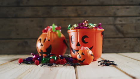 Halloween-pumpkin-buckets-full-of-halloween-candies-on-wooden-surface