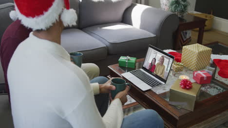 Biracial-father-with-son-using-laptop-for-christmas-video-call-with-happy-family-on-screen