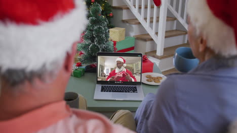 Happy-caucasian-senior-couple-on-video-call-with-santa-claus-at-christmas