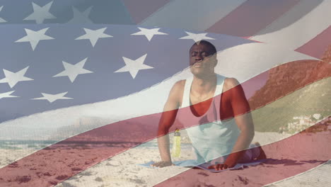 Animation-of-flag-of-united-states-of-america-over-african-american-man-practicing-yoga-on-beach