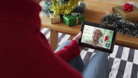 Caucasian-man-waving-and-using-tablet-for-christmas-video-call-with-smiling-man-on-screen