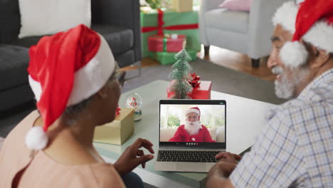 Glückliches-Afroamerikanisches-Paar-Bei-Einem-Videoanruf-Auf-Einem-Laptop-Mit-Dem-Weihnachtsmann-Zur-Weihnachtszeit