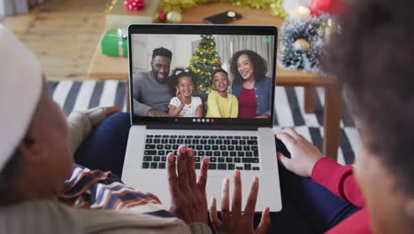 Madre-E-Hija-Afroamericanas-Usando-Una-Computadora-Portátil-Para-Una-Videollamada-Navideña-Con-La-Familia-En-La-Pantalla