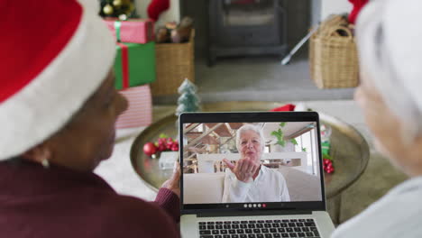 Diverse-senior-female-friends-using-laptop-for-christmas-video-call-with-happy-woman-on-screen