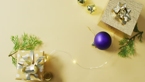 Video-of-gold-and-purple-christmas-decorations-and-presents-on-yellow-background