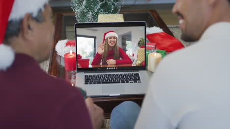 Smiling-biracial-father-with-son-using-laptop-for-christmas-video-call-with-woman-on-screen