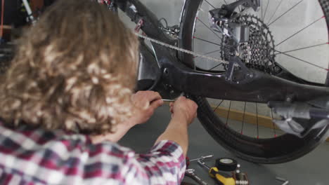 Fokussierter-Kaukasischer-Mann,-Der-Fahrrad-Mit-Werkzeugen-In-Der-Garage-Repariert