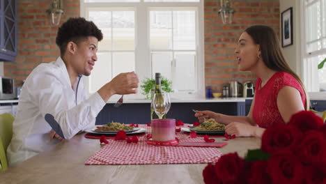 Happy-biracial-couple-having-valentine's-day-celebration-meal-at-home