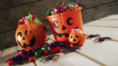 Halloween-pumpkin-buckets-full-of-halloween-candies-on-wooden-surface