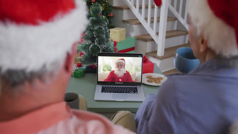 Happy-caucasian-senior-couple-couple-on-video-call-with-santa-claus-at-christmas-time