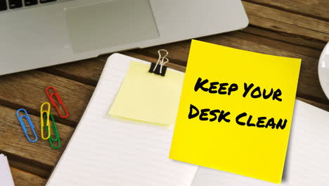 Animation-of-keep-your-desk-clean-text-on-yellow-memo-note-on-desk-with-laptop,-coffee-and-notebook