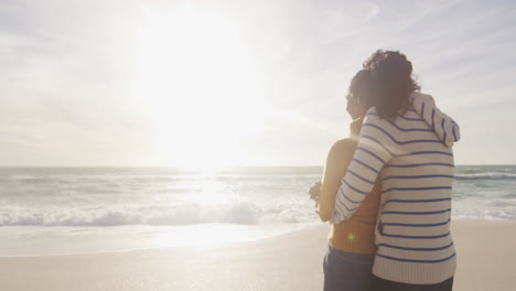Back-view-of-happy-hispanic-couple-standing-and-embracing-on-beach