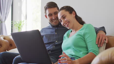 A-young-caucasian-couple-talking-and-paying-their-bills-using-a-laptop