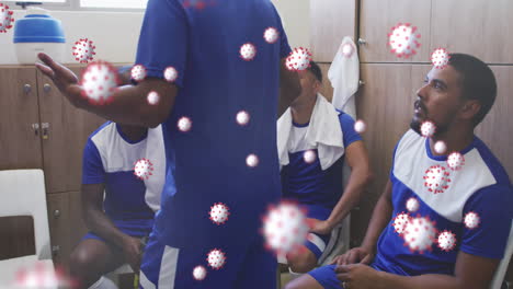 Animation-of-virus-cells-floating-over-diverse-group-of-male-football-players-in-changing-room