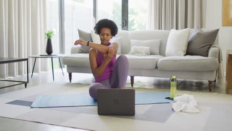 Happy-african-american-wearing-sportswear,-exercising,-using-laptop