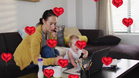 Animation-of-heart-icons-over-caucasian-mother-with-baby-talking-on-smartphone