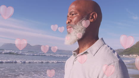 Animation-of-hearts-over-senior-african-american-man-at-beach