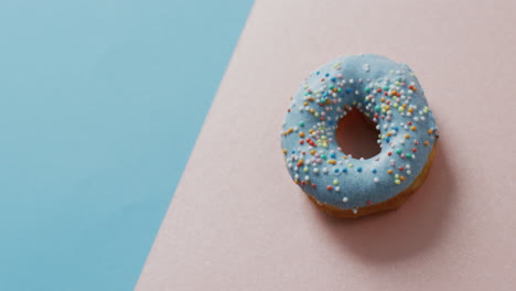 Video-Von-Donut-Mit-Zuckerguss-Auf-Blauem-Und-Rosa-Hintergrund