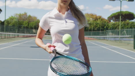 Video-of-midsection-of-caucasian-female-tennis-player-holding-racket-and-bouncing-ball