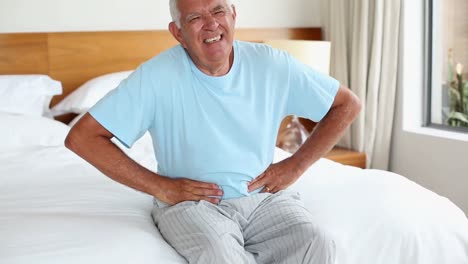 Älterer-Mann-Sitzt-Mit-Bauchschmerzen-Im-Bett