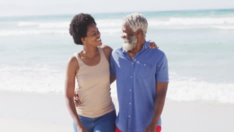 Glückliches-Afroamerikanisches-Paar,-Das-Am-Sonnigen-Strand-Spaziert-Und-Sich-Umarmt